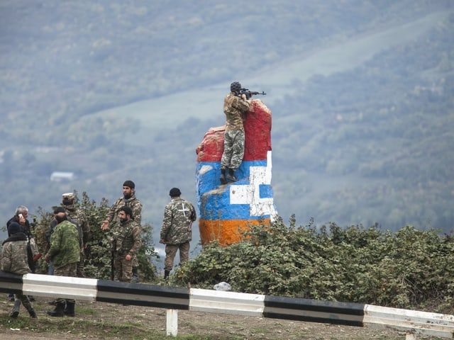 Ein Sniper beobachtet das Gebiet in der Nähe von Hadrut, er steht auf einem farbigen Felsen.