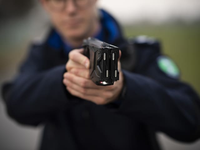 Ein Beamter der Kantonspolizei St. Gallen demonstriert einen Taser.