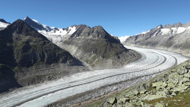 Blick von oben auf einen Gletscher und Berge.