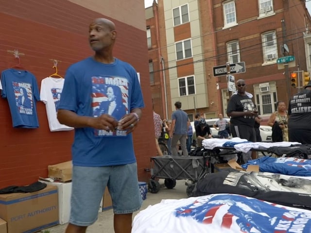 Person verkauft T-Shirts auf einem Strassenmarkt.