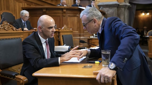 Zwei Männer in Anzug sprechen miteinander.