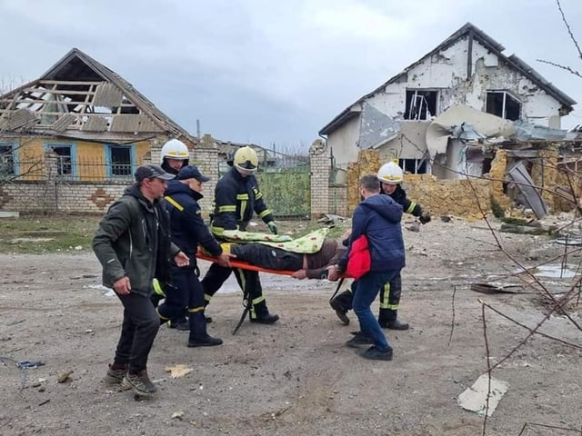 Einsatzkräfte tragen in Mykolajiw einen Verletzten auf einer Bahre.