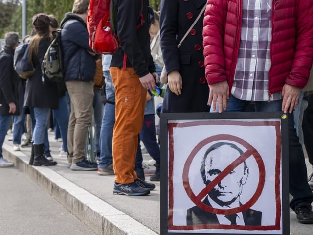 Menschen stehen in einer langen Warteschlage auf dem Trottoir.