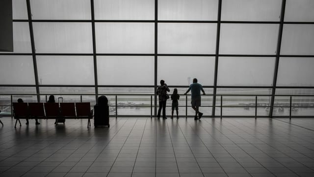 A family looks out the window at the airport