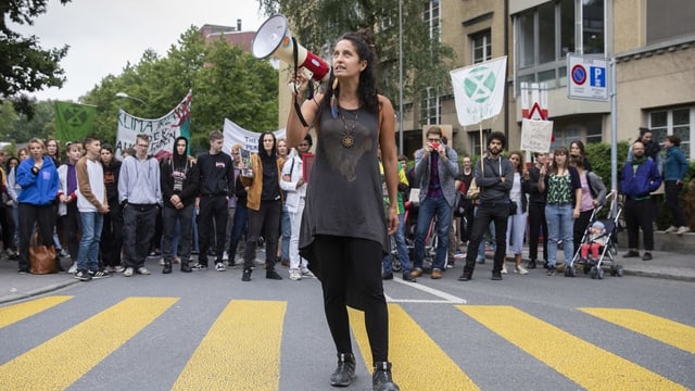 Eine Frau steht mit Megafon auf der Strasse.