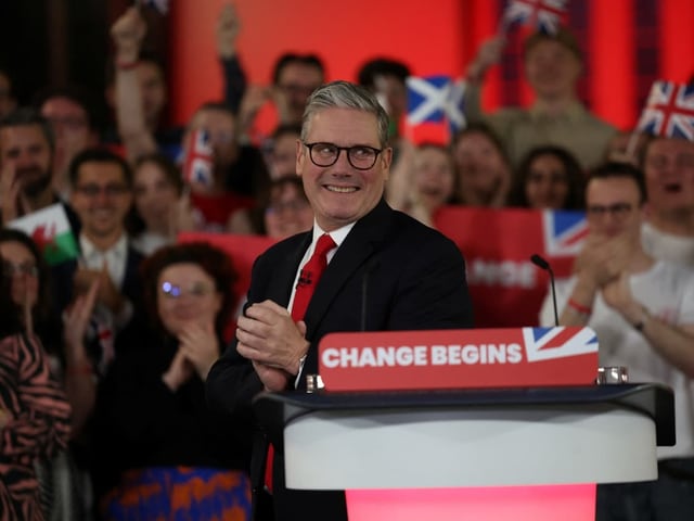 Politiker spricht vor applaudierendem Publikum mit britischen Flaggen.