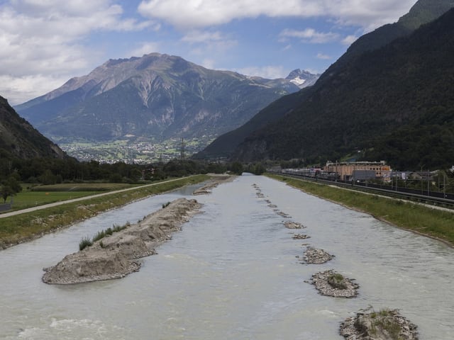 Ein Fluss fliesst durchs Tal, mittendrin erheben sich kleine Kiesinseln.