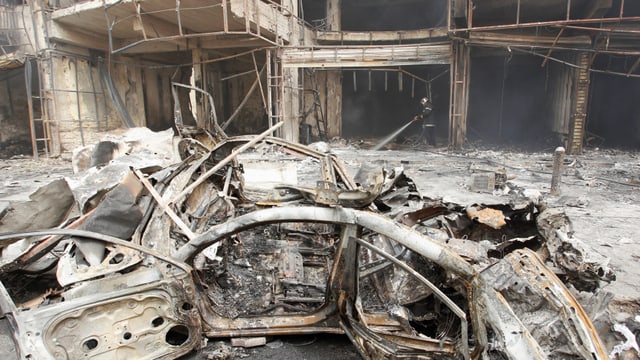 zerstörtes Auto vor zerstörtem Haus