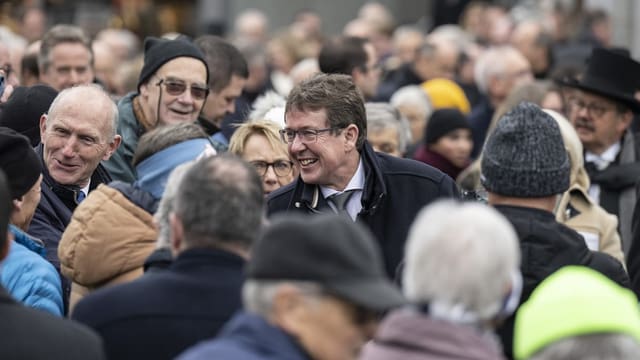 Dicht gedrängt stehen Menschen um Albert Rösti herum.