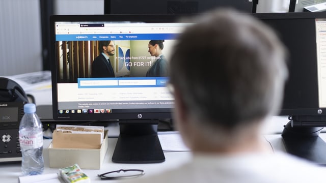 Ein Mann mit grauen Haaren sitzt vor einem Computer