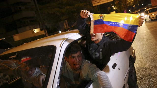 Drei Männer in einem Auto feiern den Wahlsieg der Opposition in Venezuela.