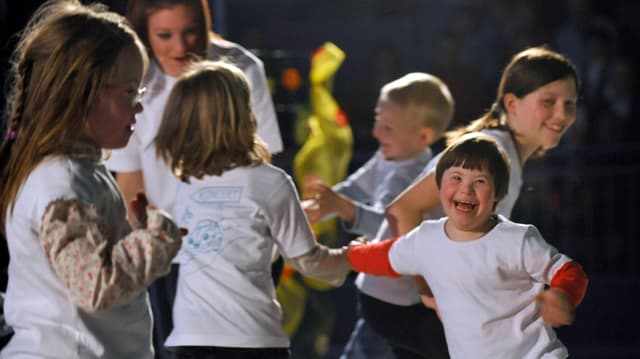 Ein Gruppe Kinder mit Down-Syndrom tanzt.