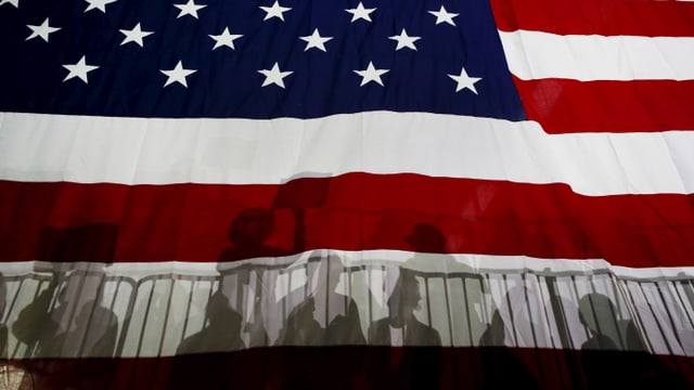 Menschen werfen Schatten auf die Flagge der USA. 