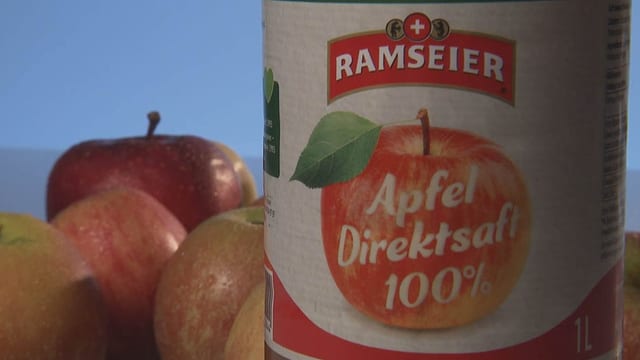 Apfelsaft-Flasche neben frischen Äpfeln