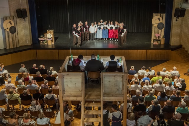 Vortagslokal mit Jodlern auf der Bühne und der Jury im Vordergrund.