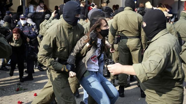 A protester is carried away by masked policemen