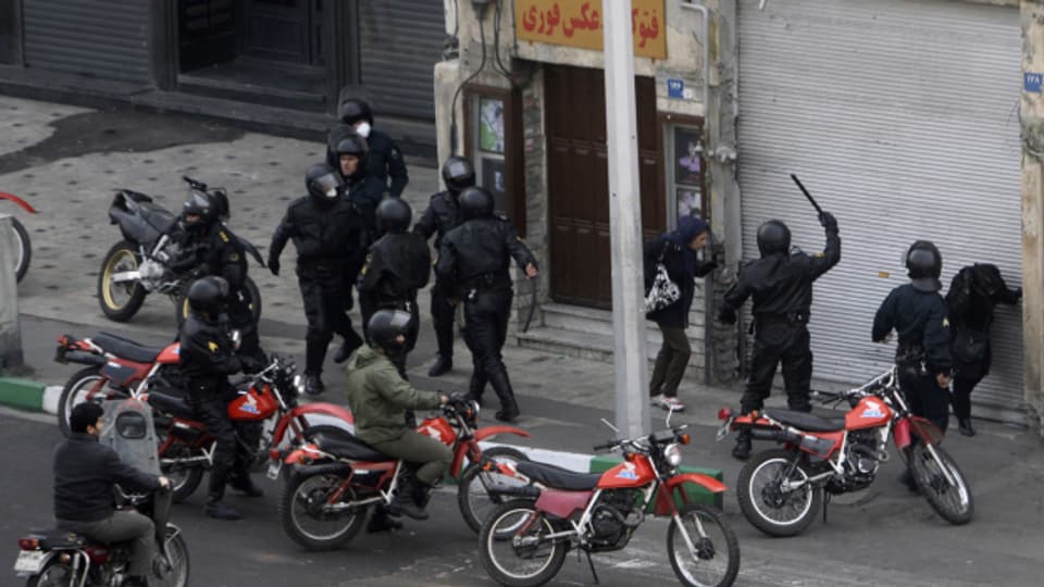 Iranische Sicherheitskräfte prügeln auf protestierende Bürgerinnen ein. An diesen Protesten 2019 war auch Amir Gudarzi beteiligt.