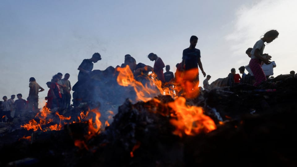 Kinder und Jugendliche suchen nach dem israelischen Angriff auf ein Zeltlager in Rafah unter verbrannten Trümmern nach Lebensmitteln.