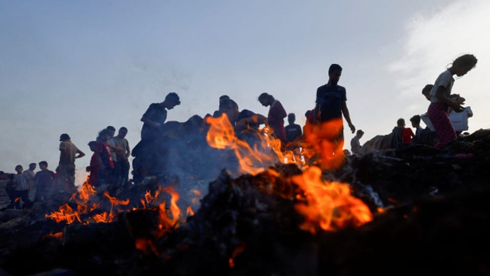 Kinder und Jugendliche suchen nach dem israelischen Angriff auf ein Zeltlager in Rafah unter verbrannten Trümmern nach Lebensmitteln.