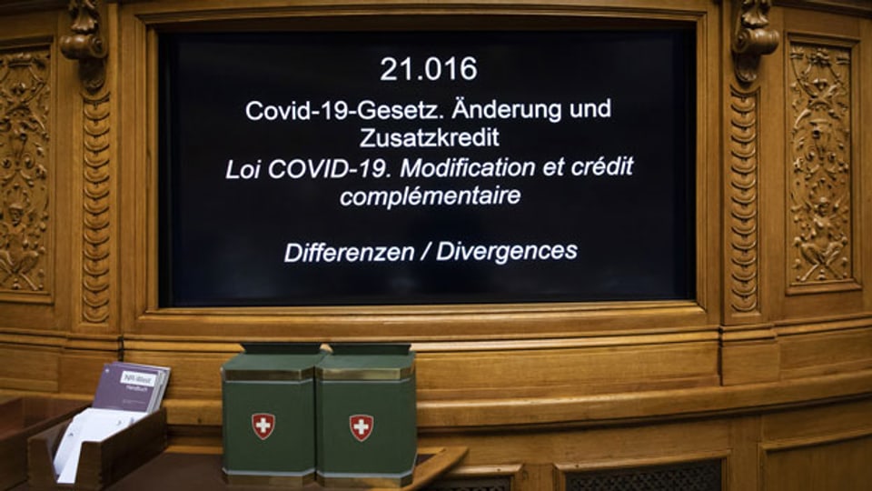Ein Bildschirm zeigt das aktuelle Thema «Covid-19-Gesetz. Änderung und Zusatzkredit» im Nationalrat an.