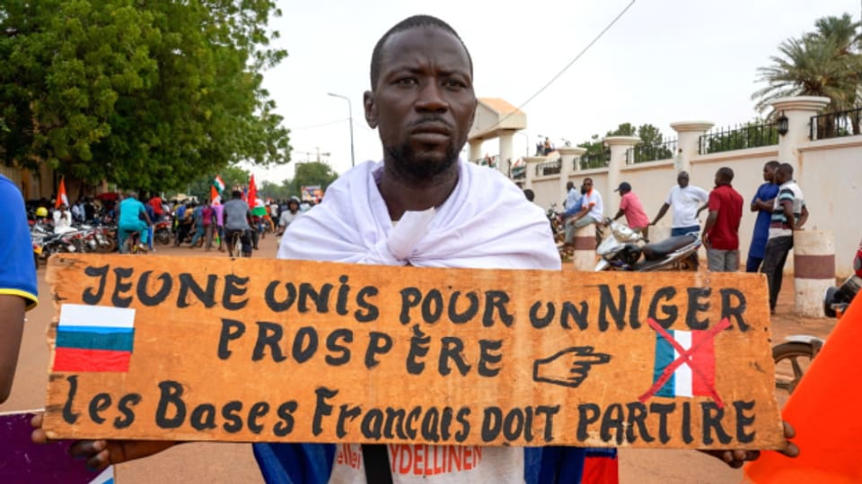 Ein Anhänger der Militärjunta zeigt ein Schild mit der Aufschrift "Vereinte Jugend für ein blühendes Niger, französische Basen müssen weg".