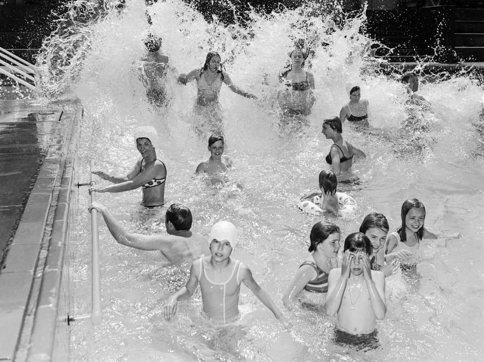 Schwarz-Weiss-Foto von Kindern, die in einem Pool spielen und planschen.