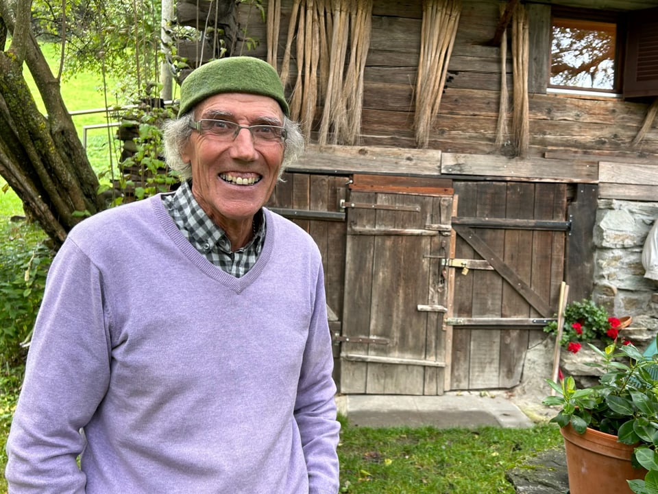 Ein älterer Mann in einem violetten Pullover mit einem grünen Beret. 