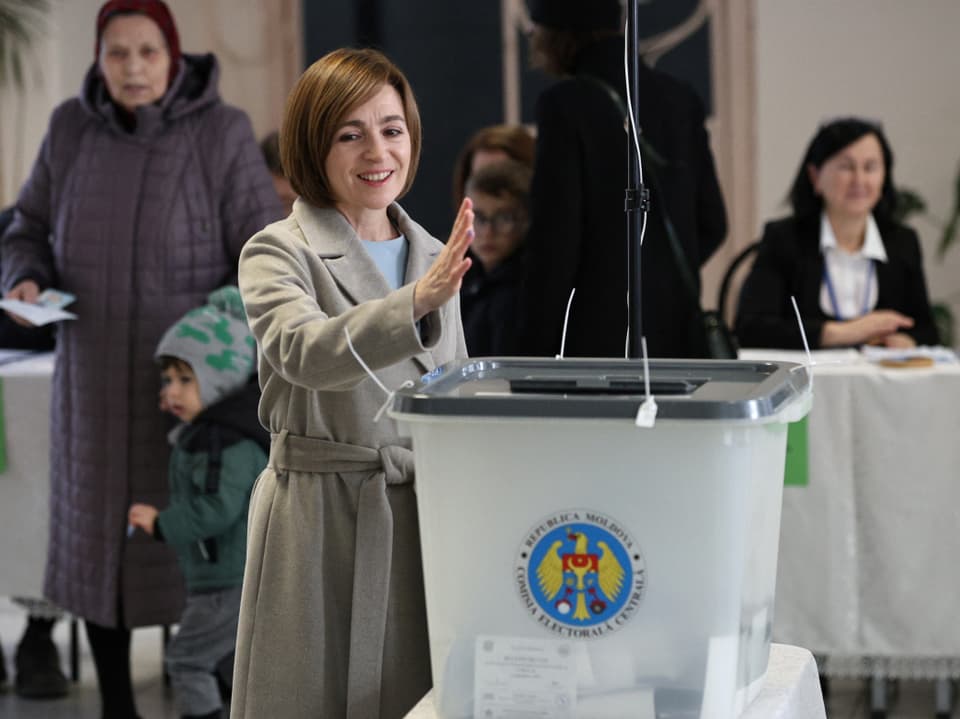 Maia Sandu gibt Wahlzettel in Wahlurne ab, Personen im Hintergrund.