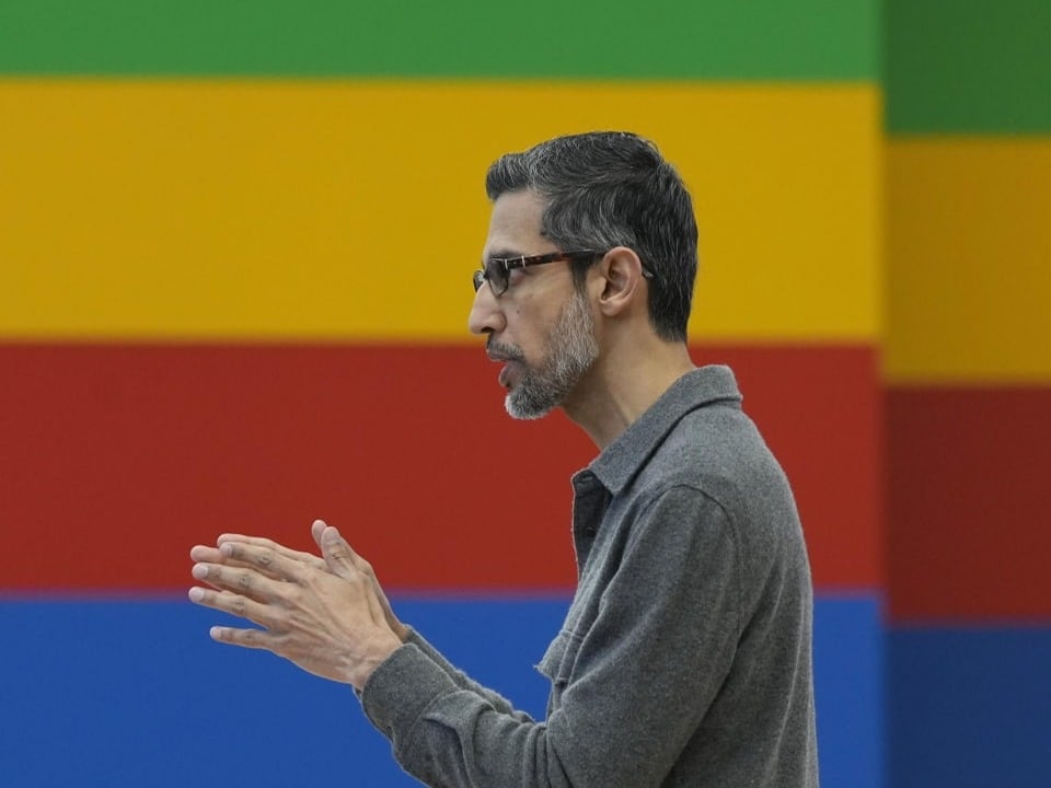 Mann mit Brille vor farbigem Hintergrund.