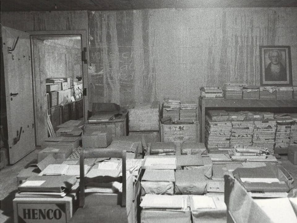 Archivraum mit Stapeln von Akten und Dokumenten in Kisten.