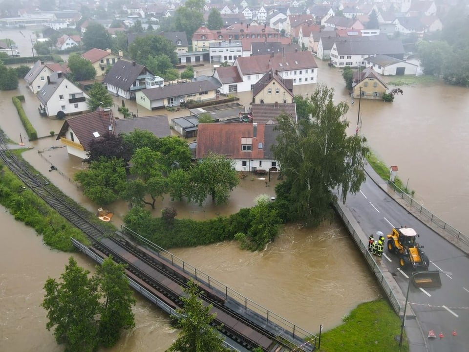 Luftaufnahme einer überschwemmten Stadt mit Gebäuden und Strassen.