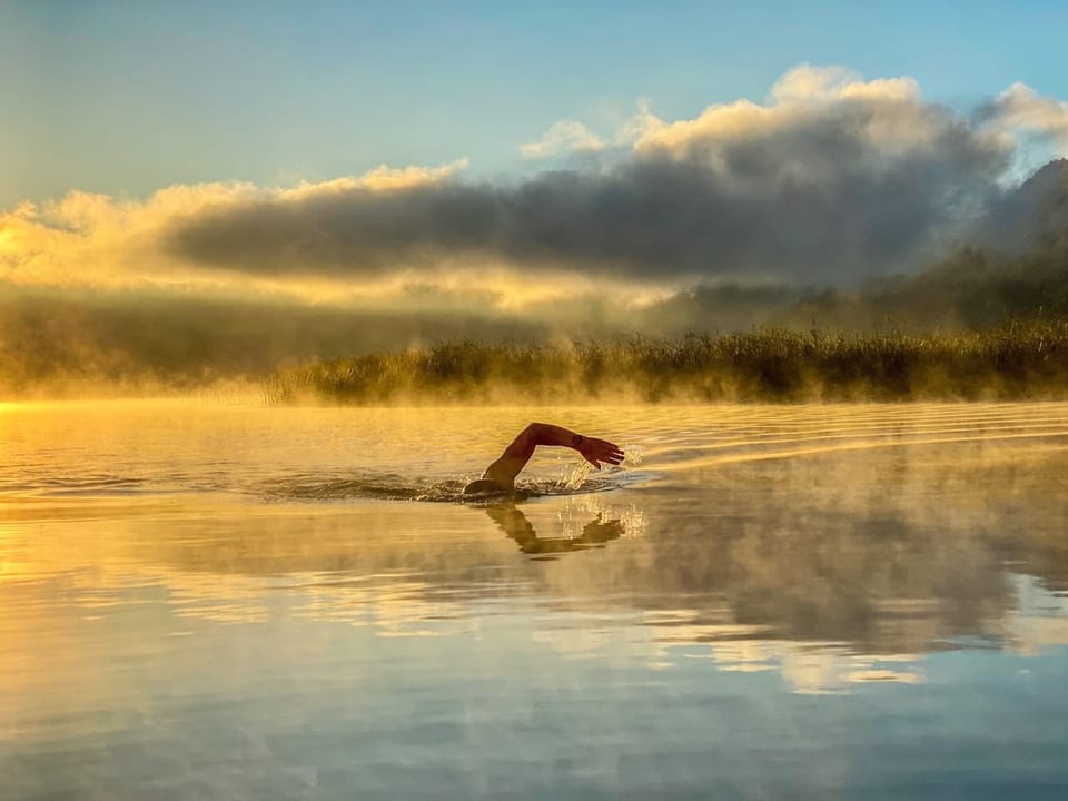 Schwimmer im Morgendunst auf einem See.