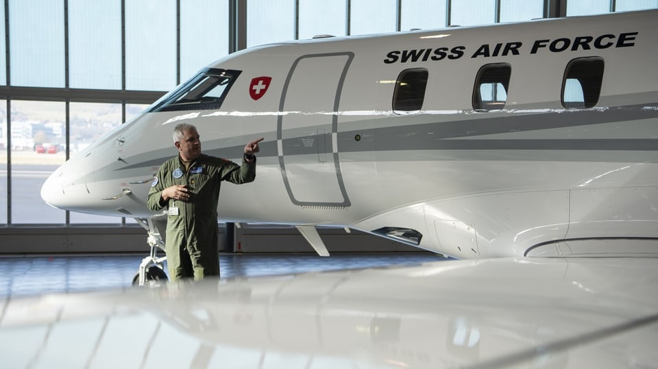 Er trägt einen grünen Anzug. Aufschrift auf Flugzeug: Swiss Air Force.