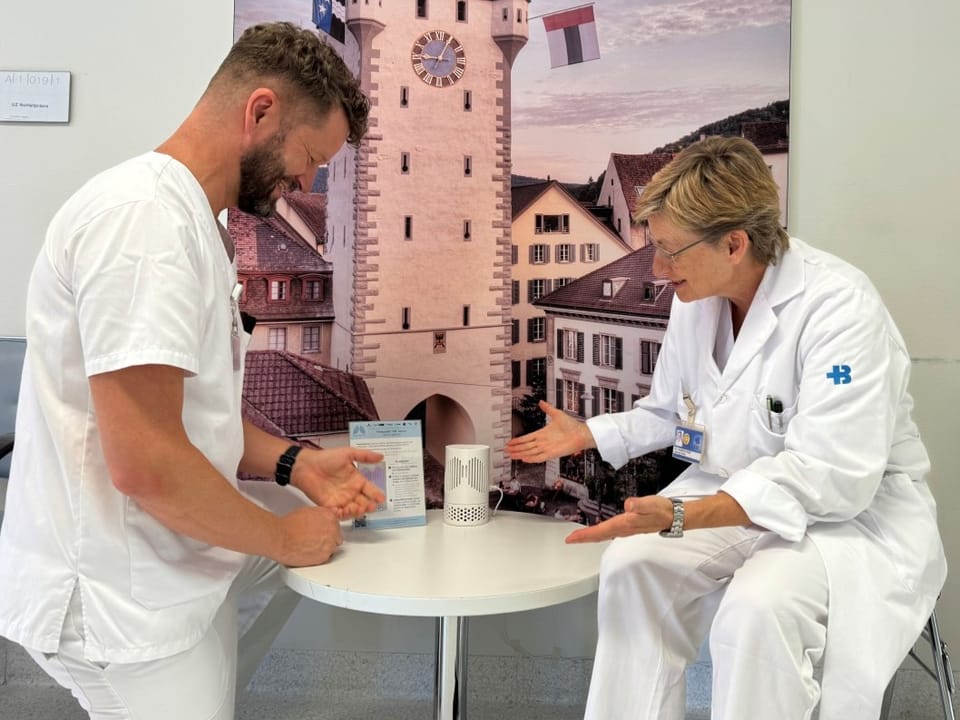 Zwei medizinische Fachkräfte besprechen ein Gerät auf einem Tisch.