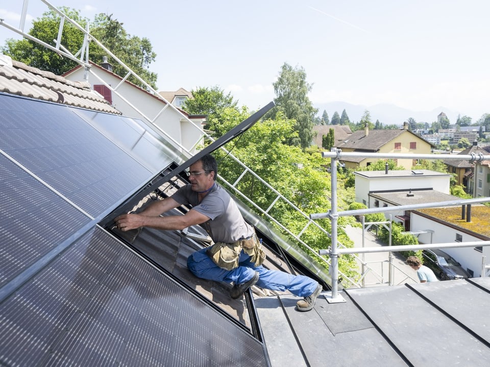 Handwerker installiert Solarpanel auf einem Dach.