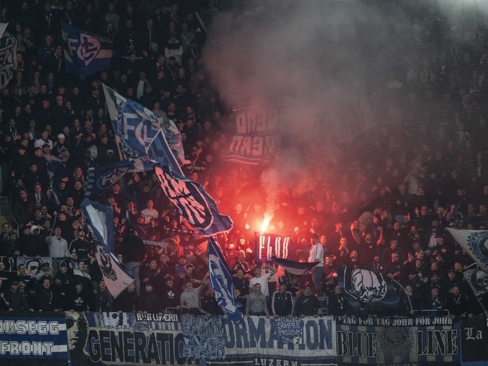 Menschenmenge mit Fahnen und Pyrotechnik im Stadion.