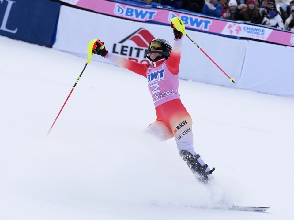 Skifahrer mit erhobenen Armen nach dem Rennen im Schnee.