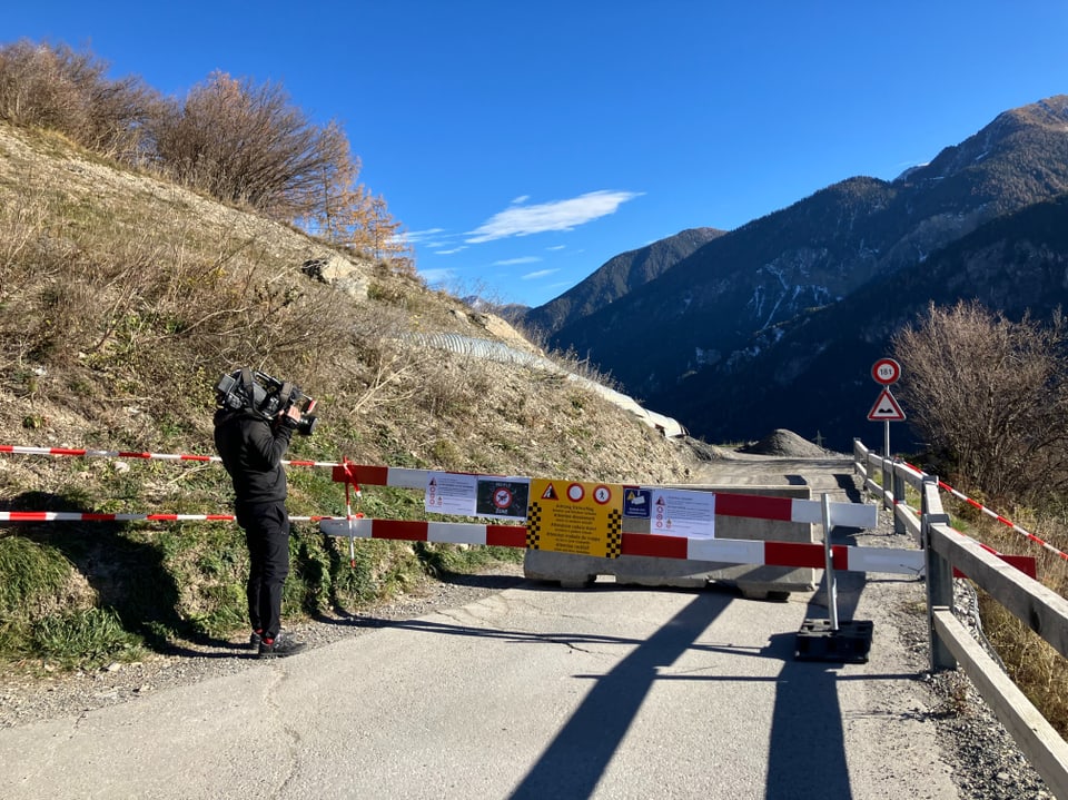 Kameramann filmt gesperrte Bergstrasse mit Warnschildern.