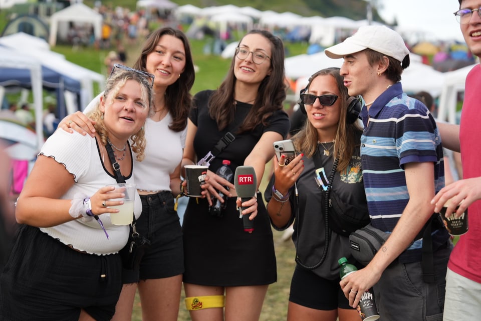 Gruppe von Menschen auf einem Outdoor-Event mit Mikrofon und Getränken am Open Air Lumnezia 2024.