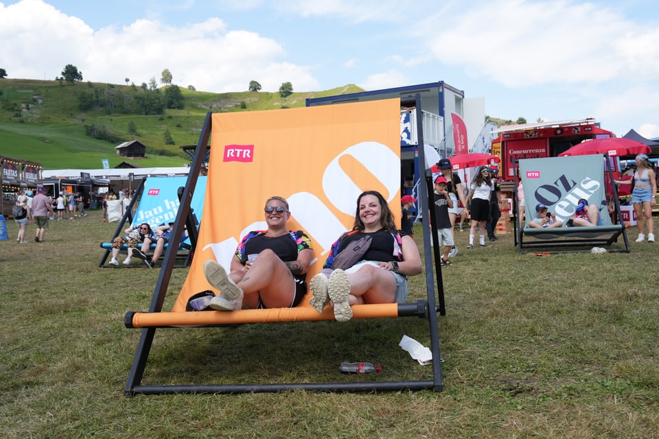 Zwei Personen auf grossem Stuhl bei Outdoor-Event.