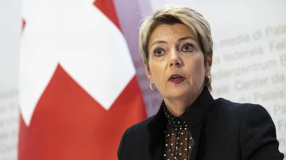 Frau mit kurzen Haaren vor Schweizer Flagge.