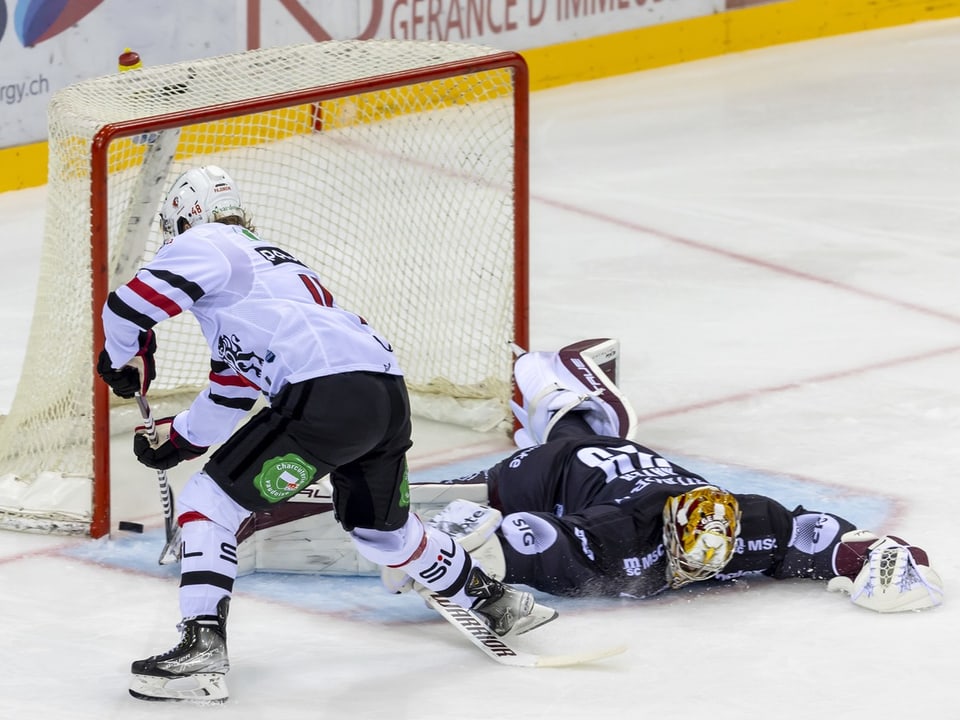 Eishockeyspieler schiesst Tor gegen liegenden Torwart.