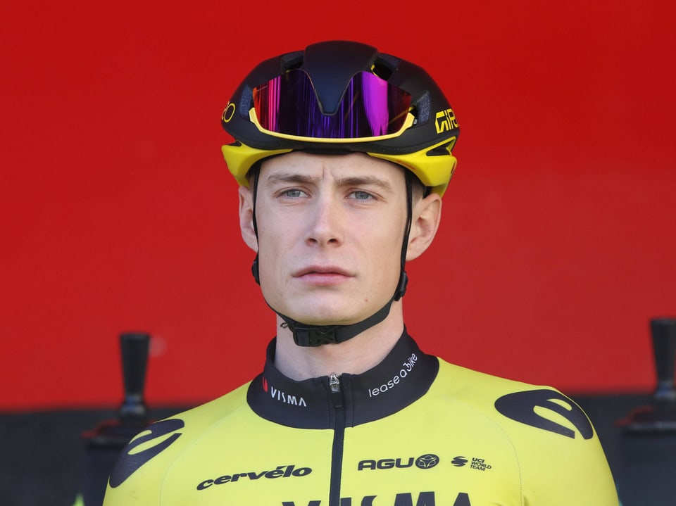 Radrennfahrer mit gelbem Helm und Trikot vor rotem Hintergrund.
