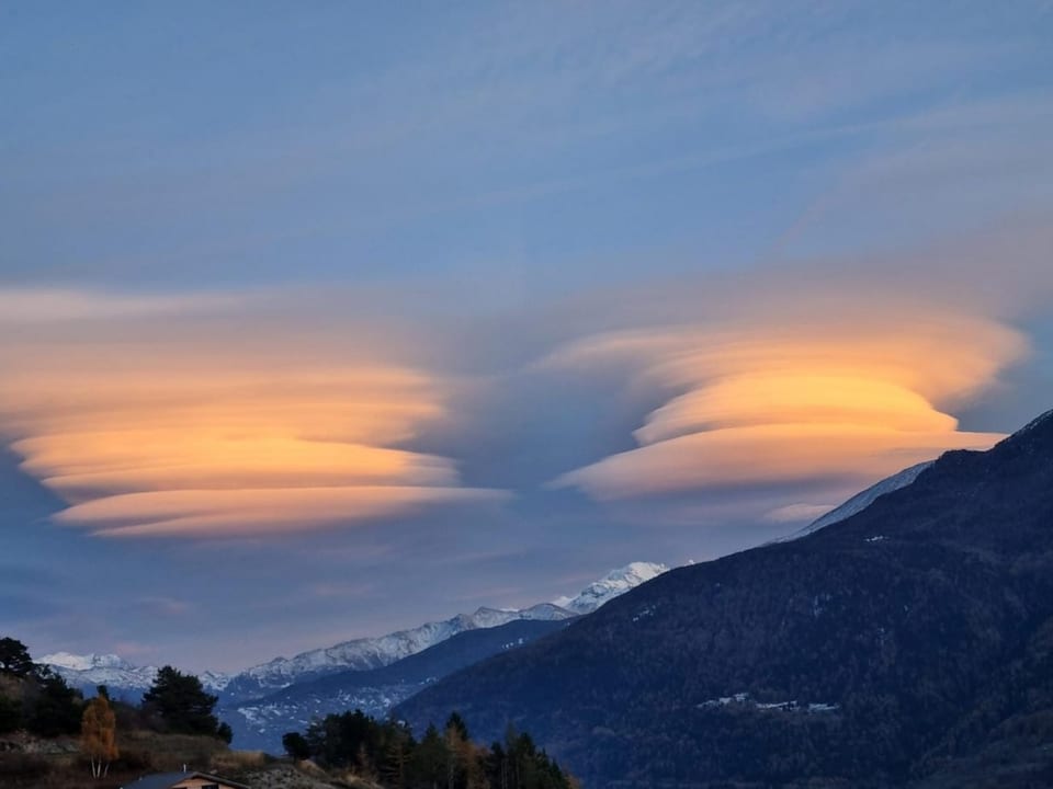 Lenticularis-Wolken über Berglandschaft bei Sonnenuntergang.