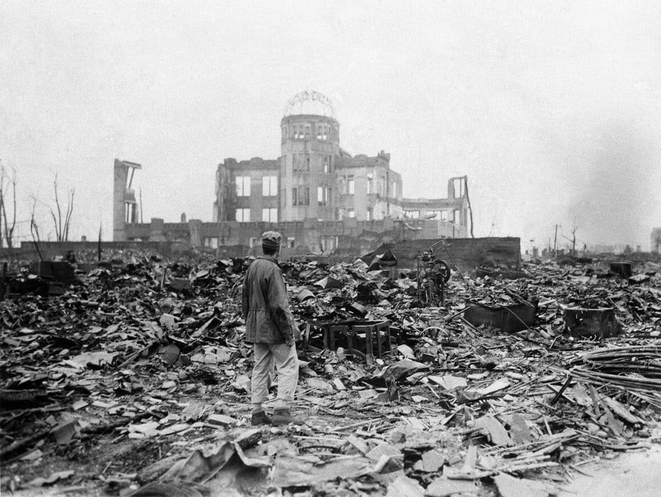 Ein Mann steht im zerstörten Hiroshima vor der Fassade eines Gebäudes.