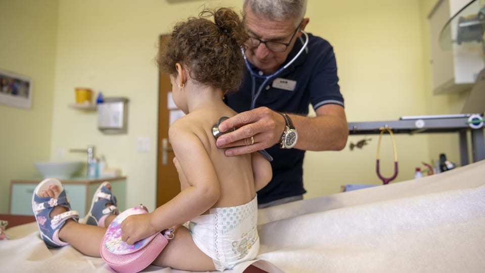 Arzt untersucht den Rücken eines kleinen Mädchens in der Arztpraxis.