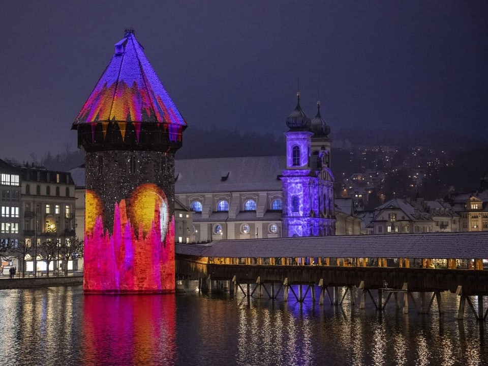 Ein Turm in der Nacht leuchtet in roten und blauen Farben.