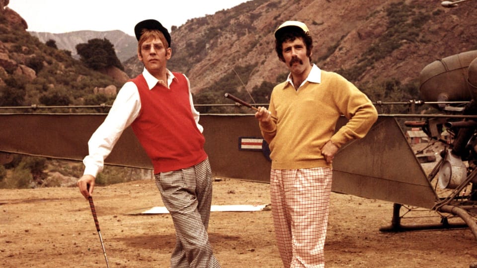 Die zwei Schauspieler Elliottt Gould und Donald Sutherland im Film «Mash», verkleidet in Golfer-Outfits in der Wüste.