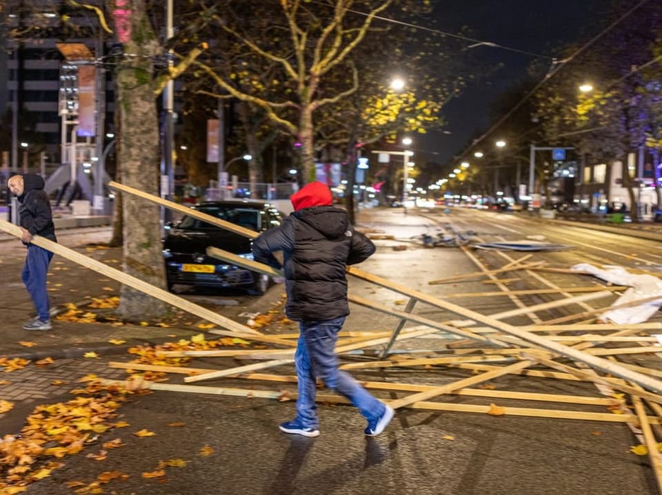 Personen räumen Holz von der Strasse bei Nacht.