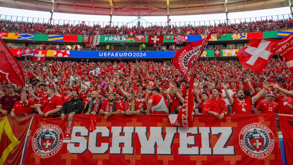 Schweizer Fussballfans im Stadion mit Schweiz-Banner bei der UEFA Euro 2024.